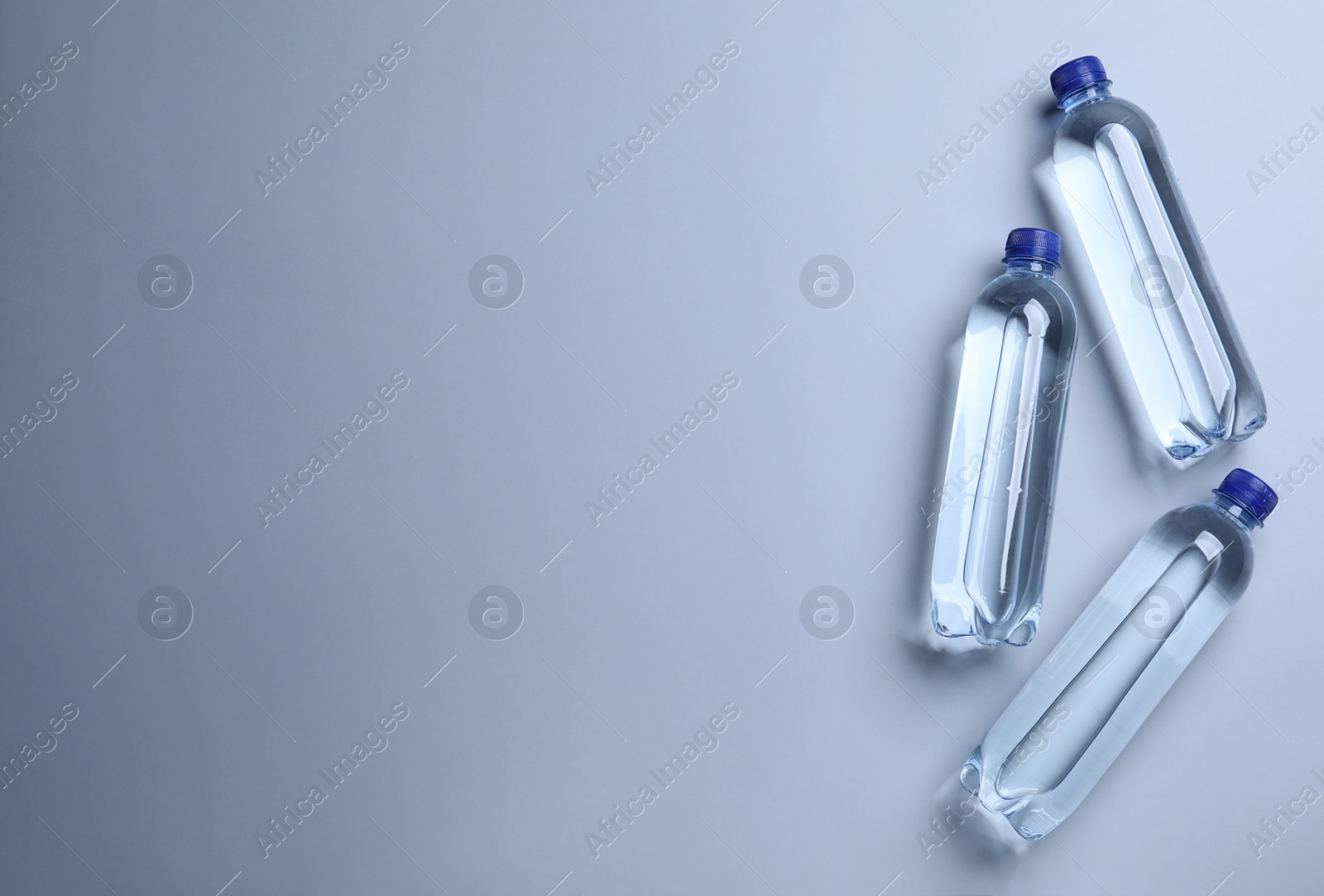 Photo of Plastic bottles with water on white background, flat lay. Space for text