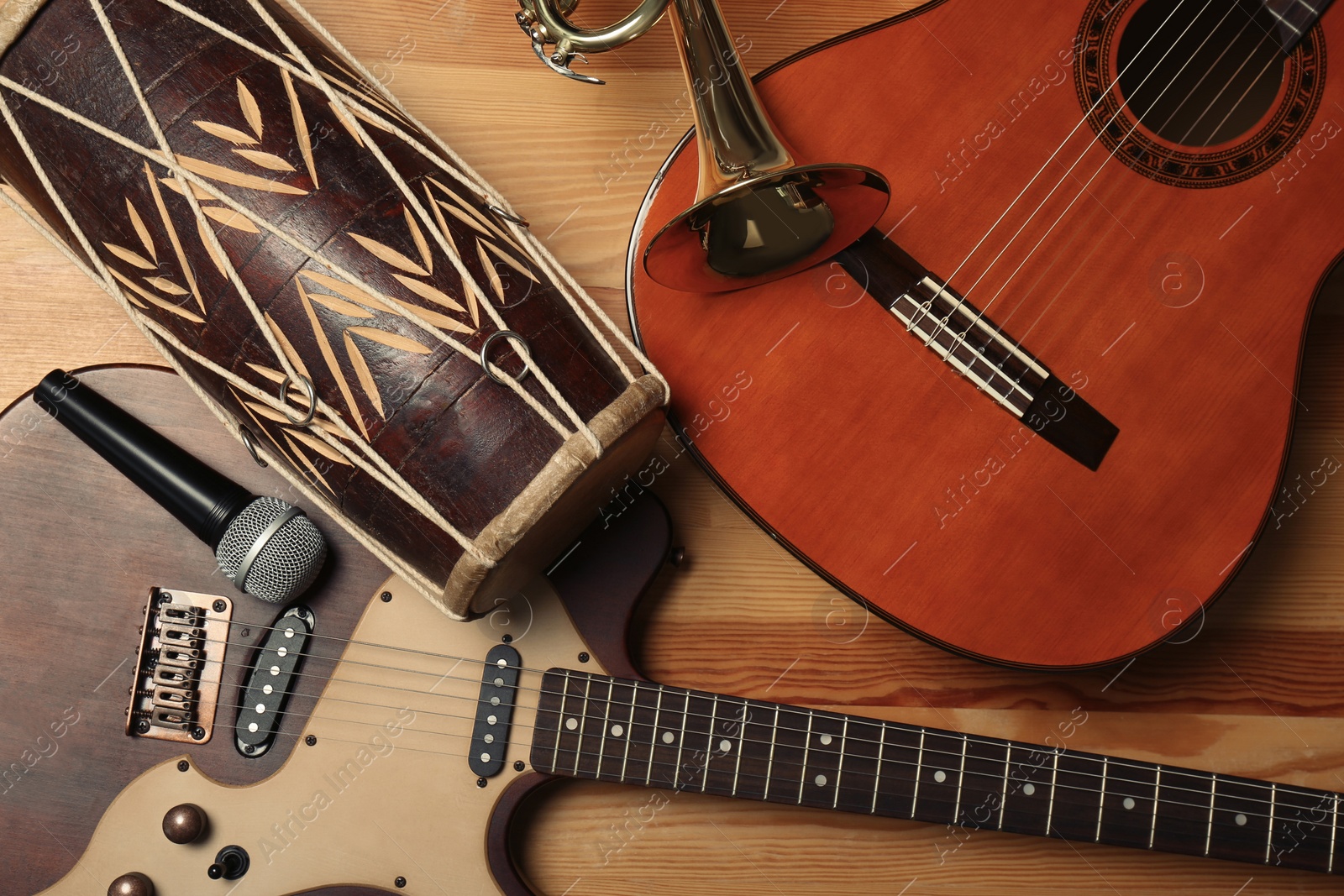 Photo of Set of different musical instruments and microphone on wooden background, flat lay