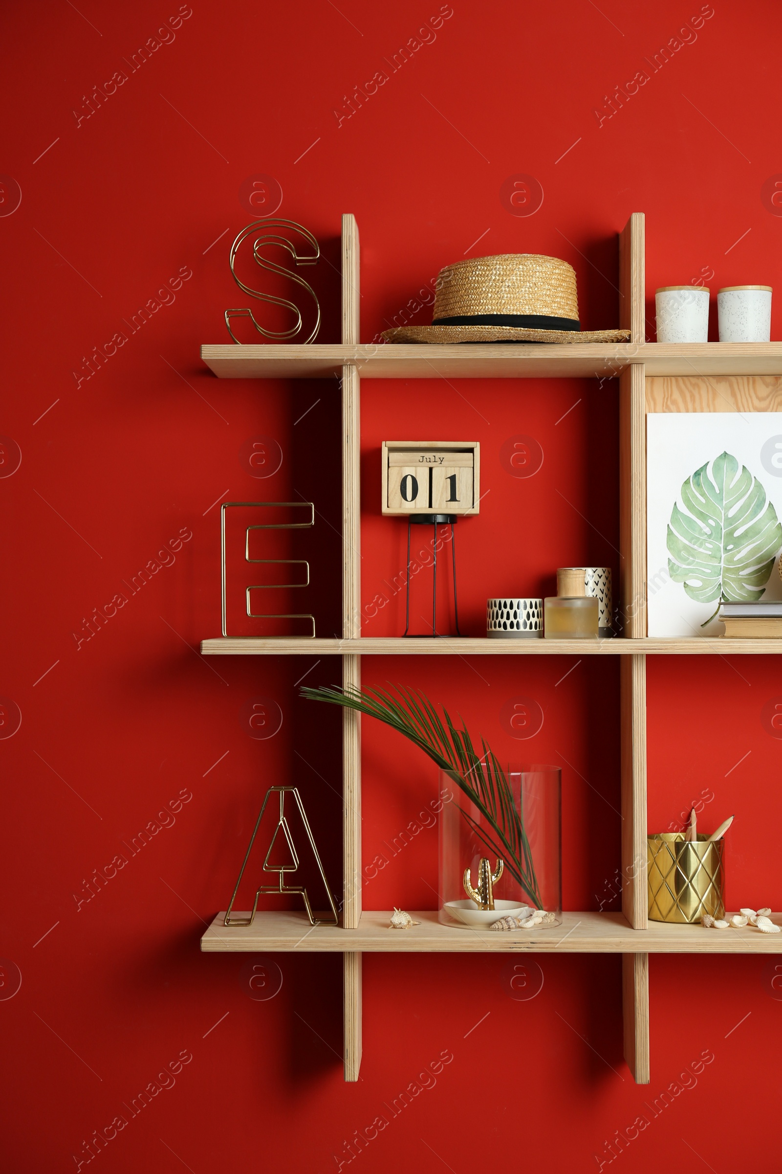 Photo of Stylish wooden shelves with decorative elements on red wall