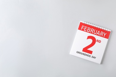 Photo of Top view of calendar with date February 2nd on light background, space for text. Groundhog day