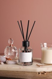 Photo of Composition with aromatic reed air freshener on wooden table near pink wall