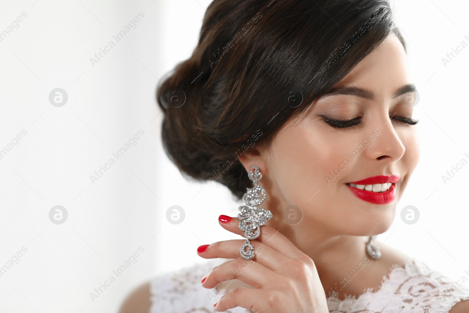 Photo of Beautiful young woman with elegant jewelry on light background. Space for text