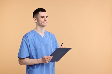 Photo of Portrait of smiling medical assistant with clipboard on beige background. Space for text
