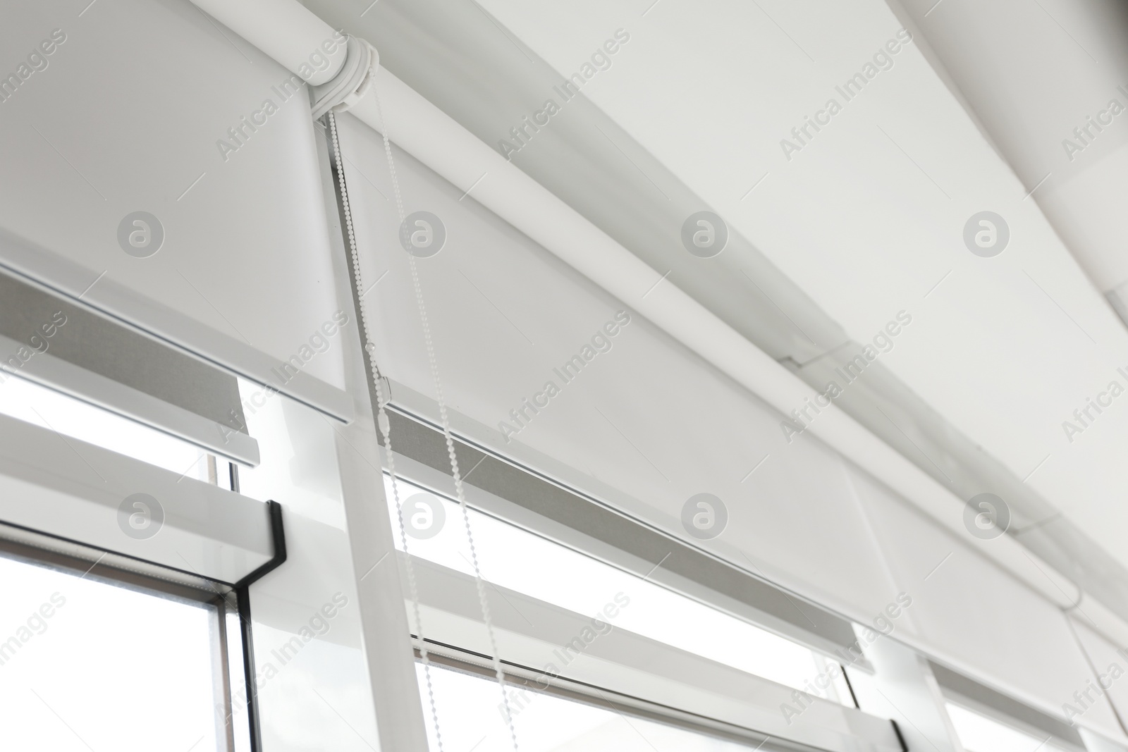 Photo of Modern window with white roller blinds indoors