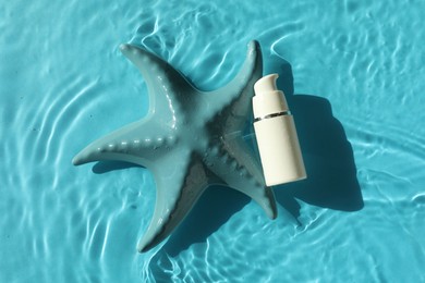 Moisturizing cream and sea star in water on light blue background, top view