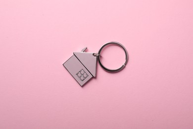 Photo of Metallic keychain in shape of house on pink background, top view
