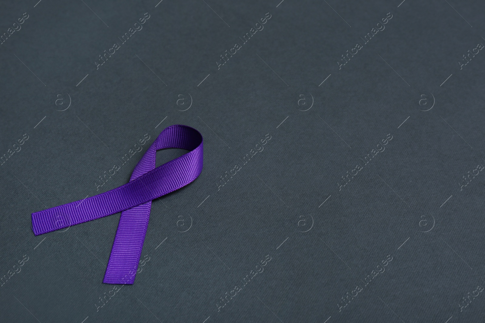 Photo of Purple awareness ribbon on black background, space for text