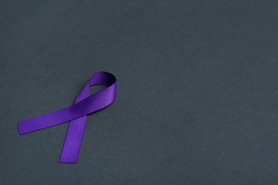 Photo of Purple awareness ribbon on black background, space for text