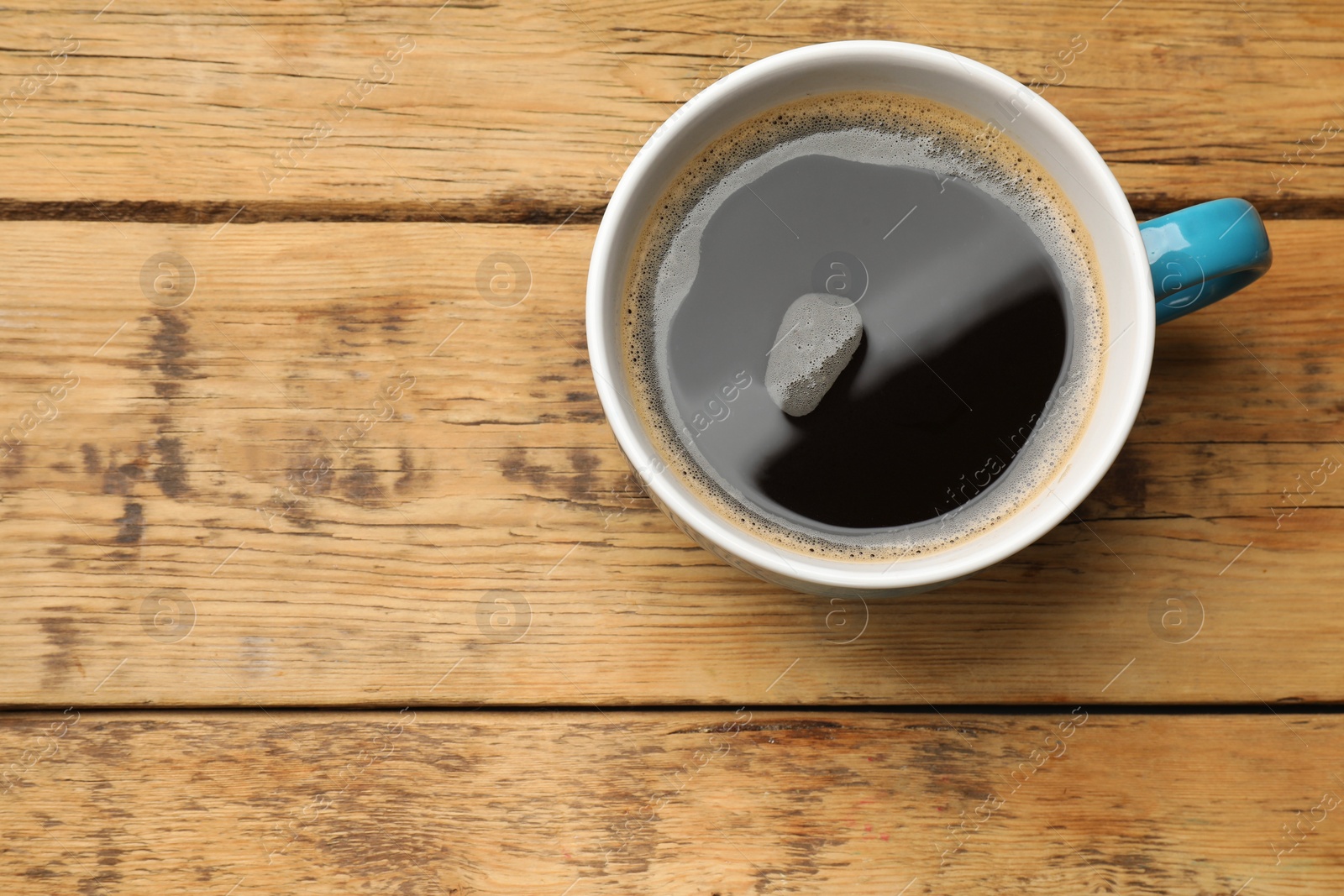 Photo of Cup of aromatic coffee on wooden table, top view. Space for text