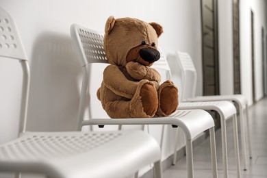 Photo of Cute lonely teddy bear on chair indoors