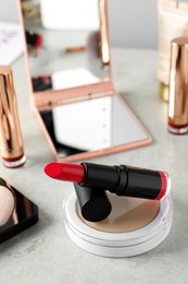 Photo of Beautiful pink lipstick and cosmetic products on light gray table