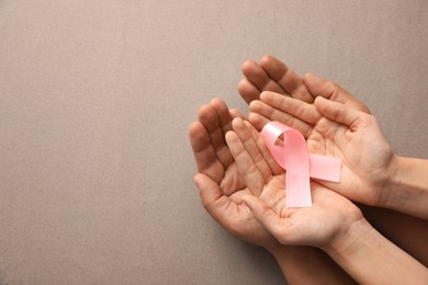 Photo of Couple holding pink ribbon on grey background, top view. Breast cancer awareness concept