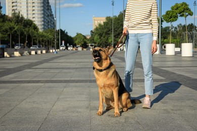 Photo of Woman with her aggressive dog on city street, closeup