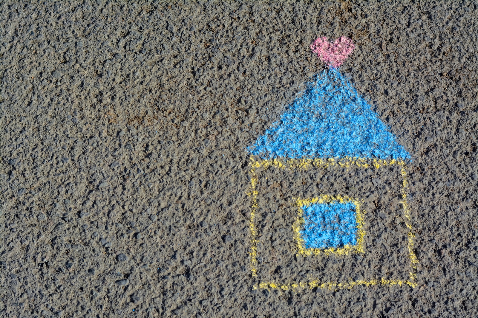 Photo of House with heart drawn by blue and yellow chalk on asphalt, top view. Space for text