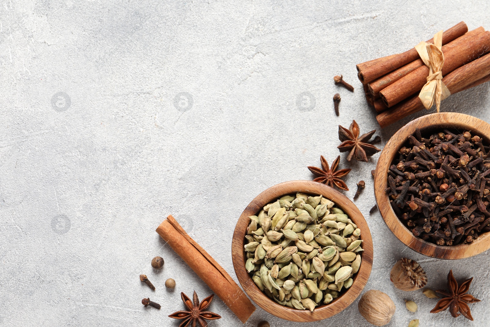 Photo of Different aromatic spices on light textured table, flat lay. Space for text