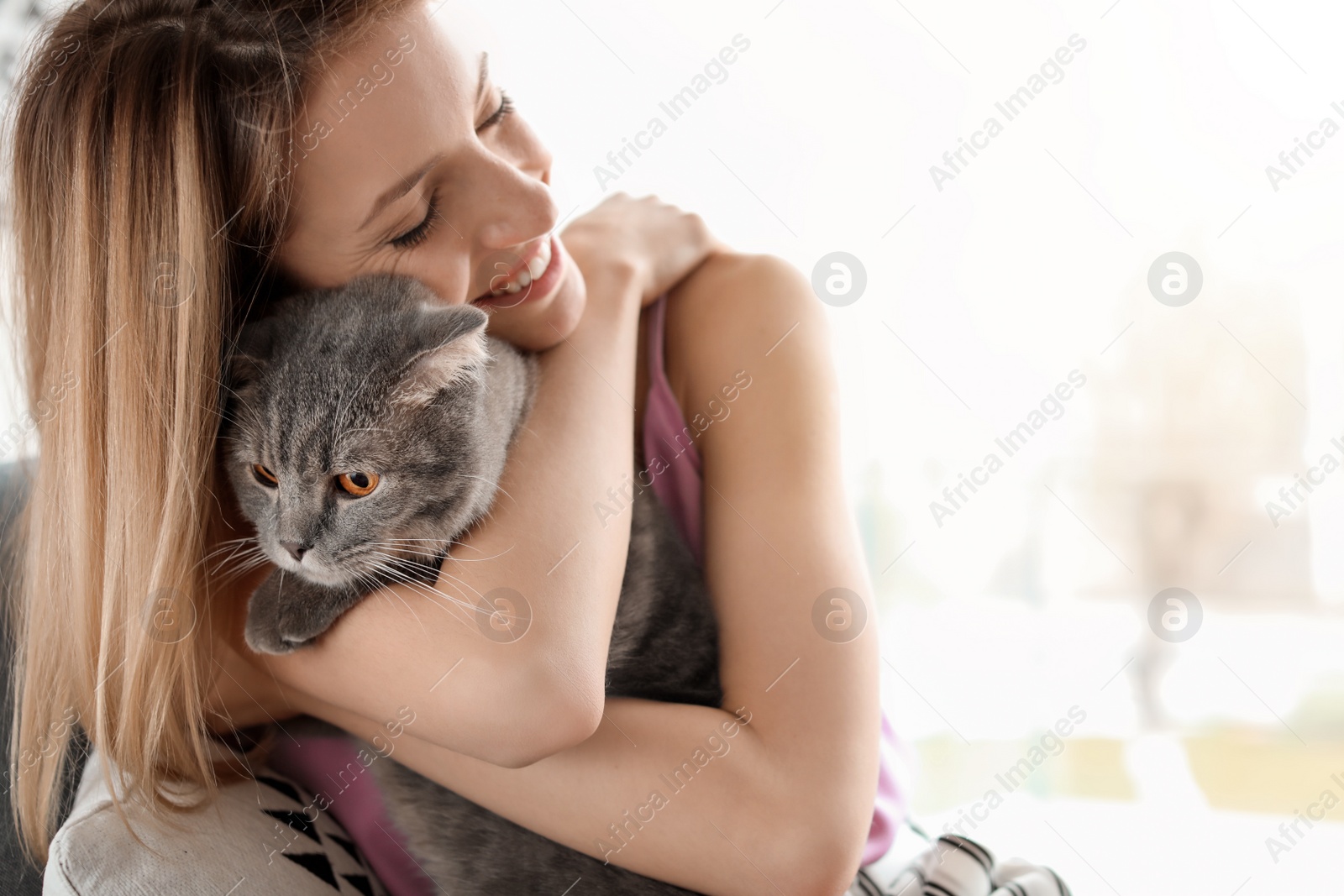 Photo of Young woman with her cute pet cat in armchair at home