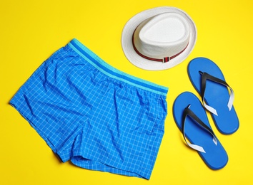 Flat lay composition with stylish male swim trunks on color background. Beach objects