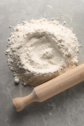 Photo of Pile of flour and rolling pin on grey marble table, top view