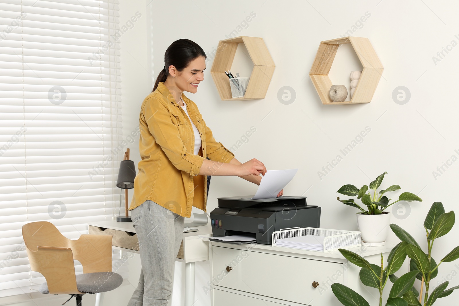 Photo of Woman using modern printer at workplace indoors