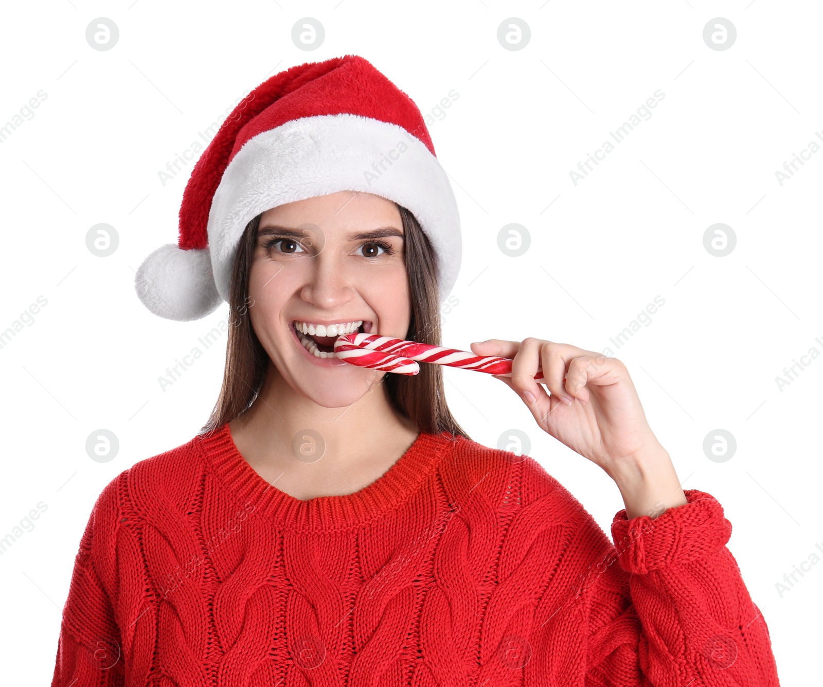 Photo of Pretty woman in Santa hat and red sweater eating candy cane on white background