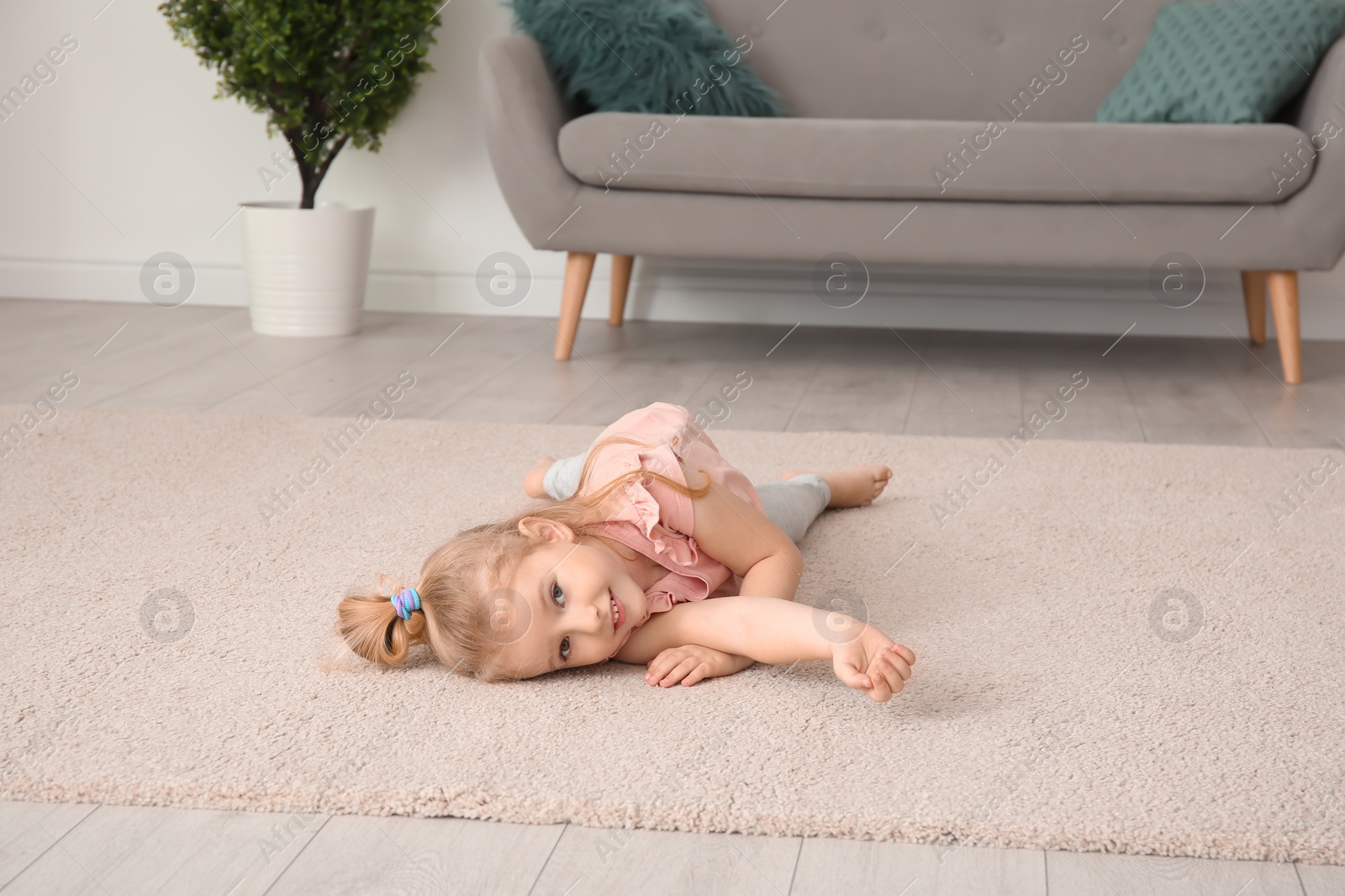 Photo of Cute little girl lying on cozy carpet at home