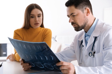 Photo of Orthopedist showing X-ray picture to patient at table in clinic