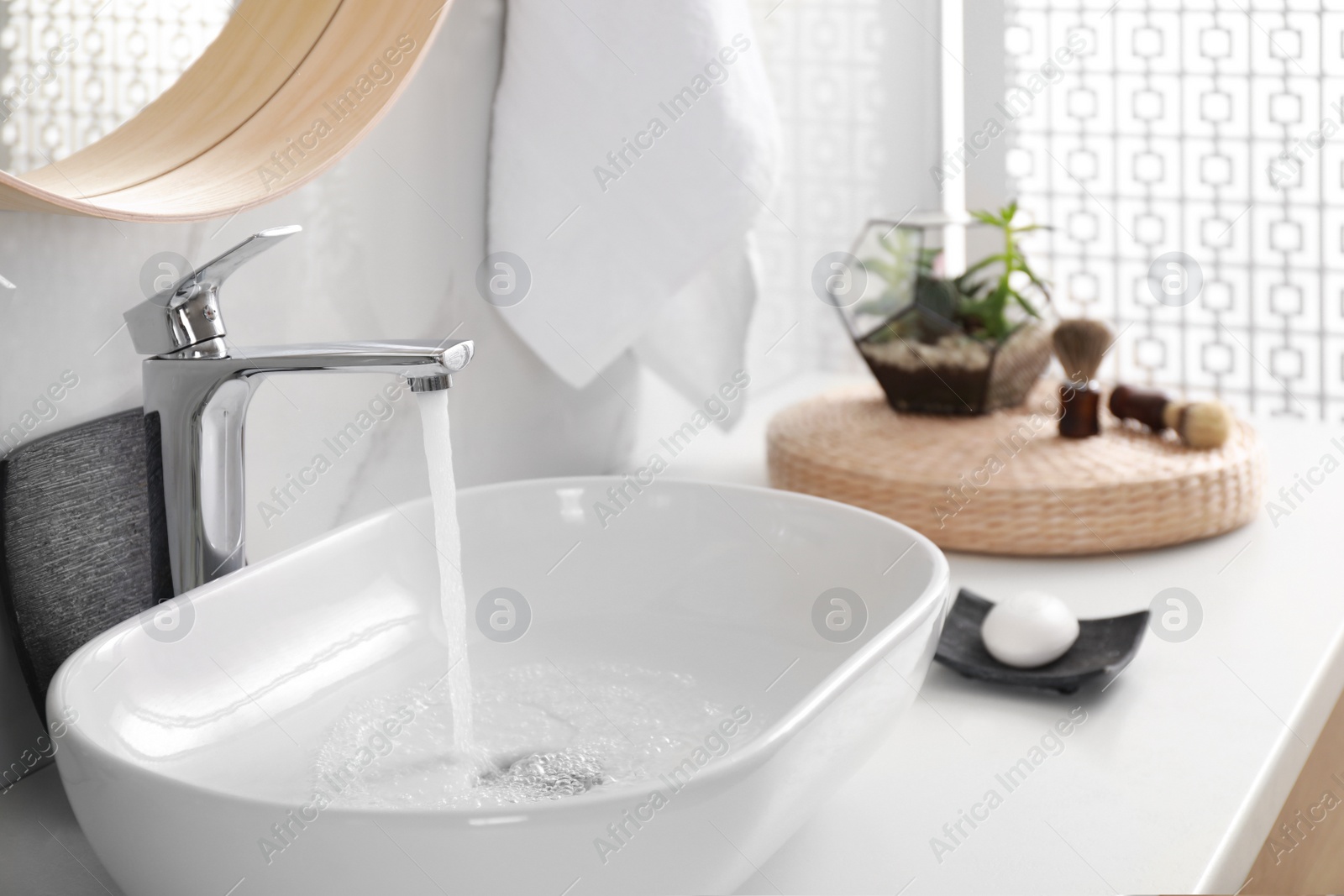 Photo of Sink with running water in stylish bathroom interior