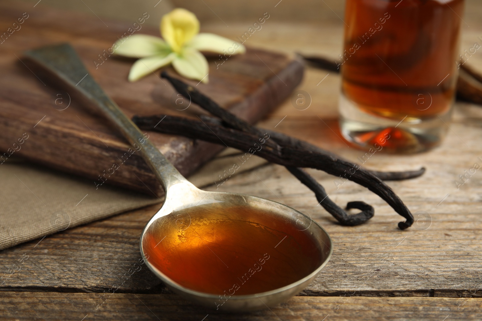 Photo of Aromatic homemade vanilla extract on wooden table, closeup