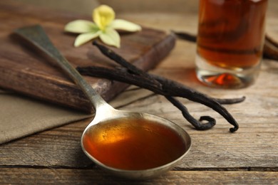 Aromatic homemade vanilla extract on wooden table, closeup