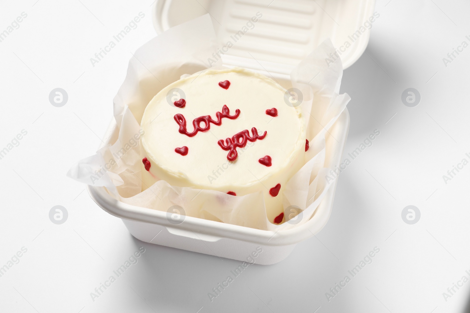 Photo of Bento cake with Love You text in takeaway box on white table. St. Valentine's day surprise