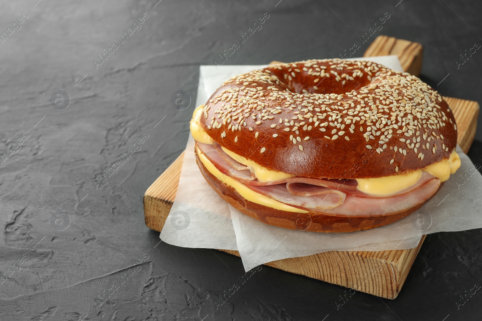 Delicious bagel with ham and cheese on grey textured table, space for text Photo of Delicious bagel with ham and cheese on grey textured table, space for text