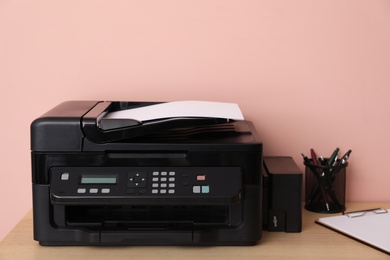 Photo of New modern printer and office supplies on wooden table