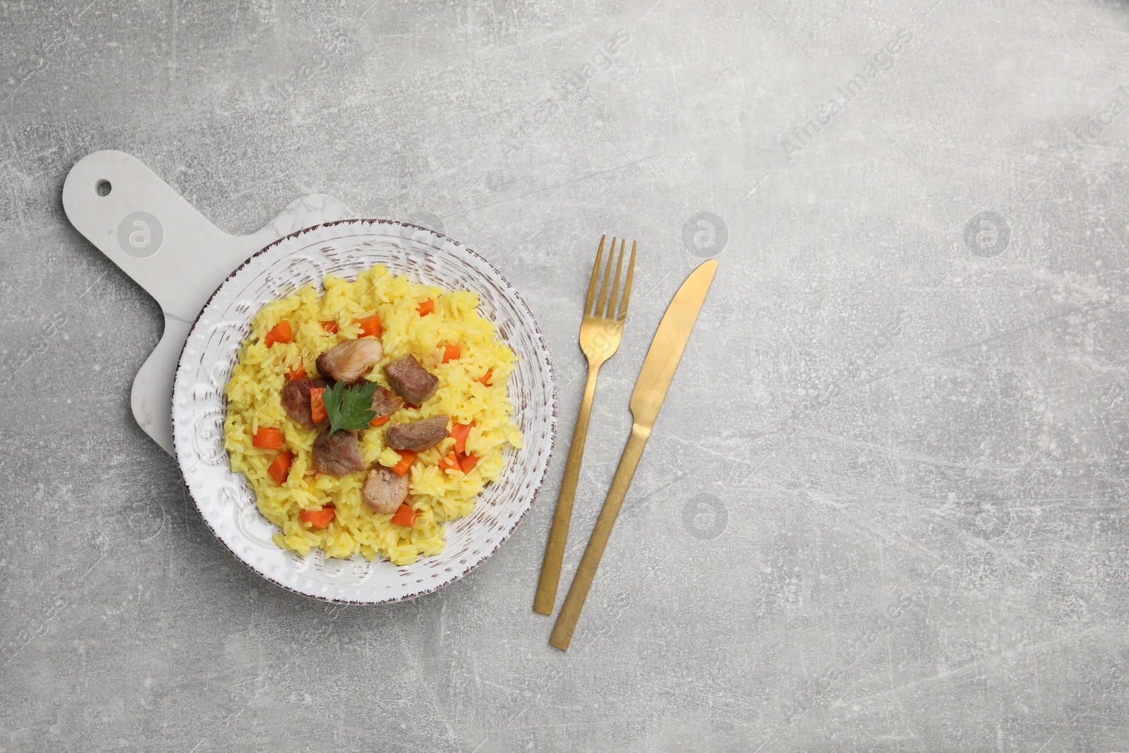 Photo of Delicious pilaf with meat served on light grey table, flat lay. Space for text