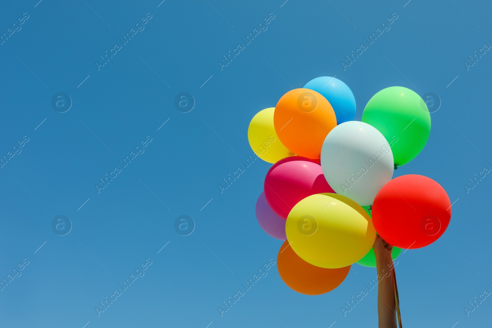 Photo of Woman with bunch of colorful balloons against blue sky, closeup. Space for text