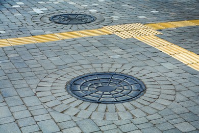 Photo of Metal sewer hatch on street tiles outdoors