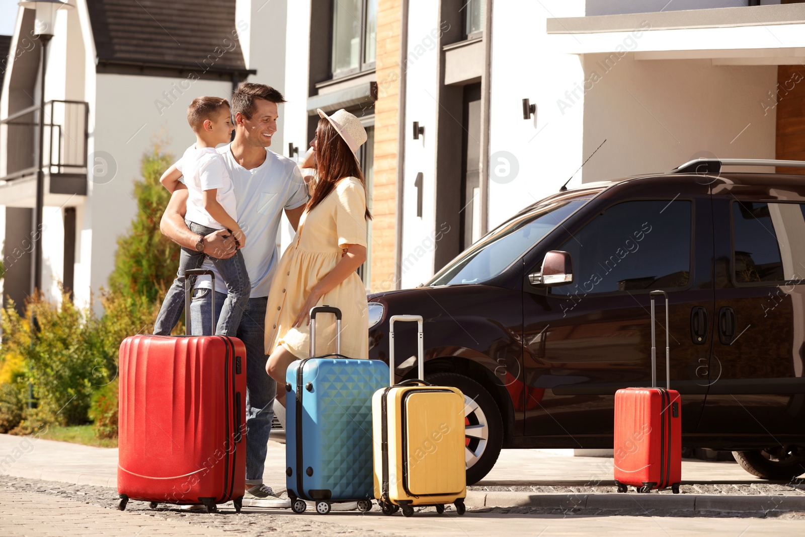 Photo of Happy family with suitcases near house outdoors. Moving day