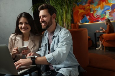 Photo of Couple with coffee and laptop spending time together in cafe, space for text