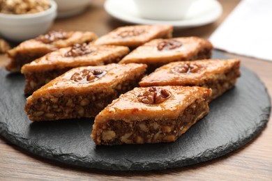 Photo of Delicious sweet baklava with walnuts on wooden table, closeup