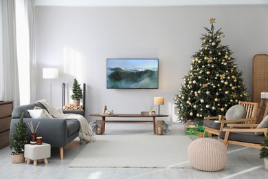 Modern TV set on light wall in room decorated for Christmas