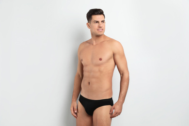 Handsome man in black underwear on white background