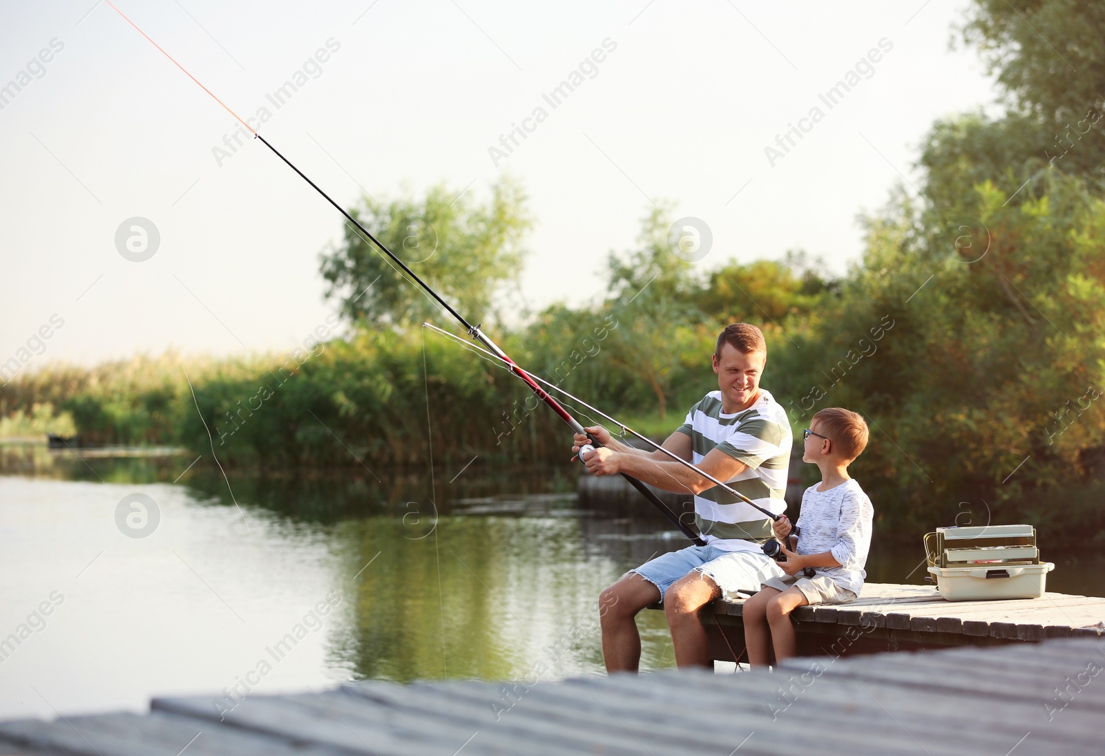 Photo of Dad and son fishing together on sunny day