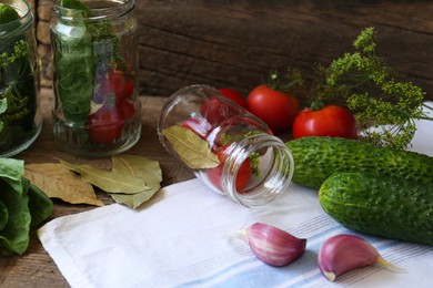 Glass jars, fresh vegetables and herbs on wooden table. Pickling recipe