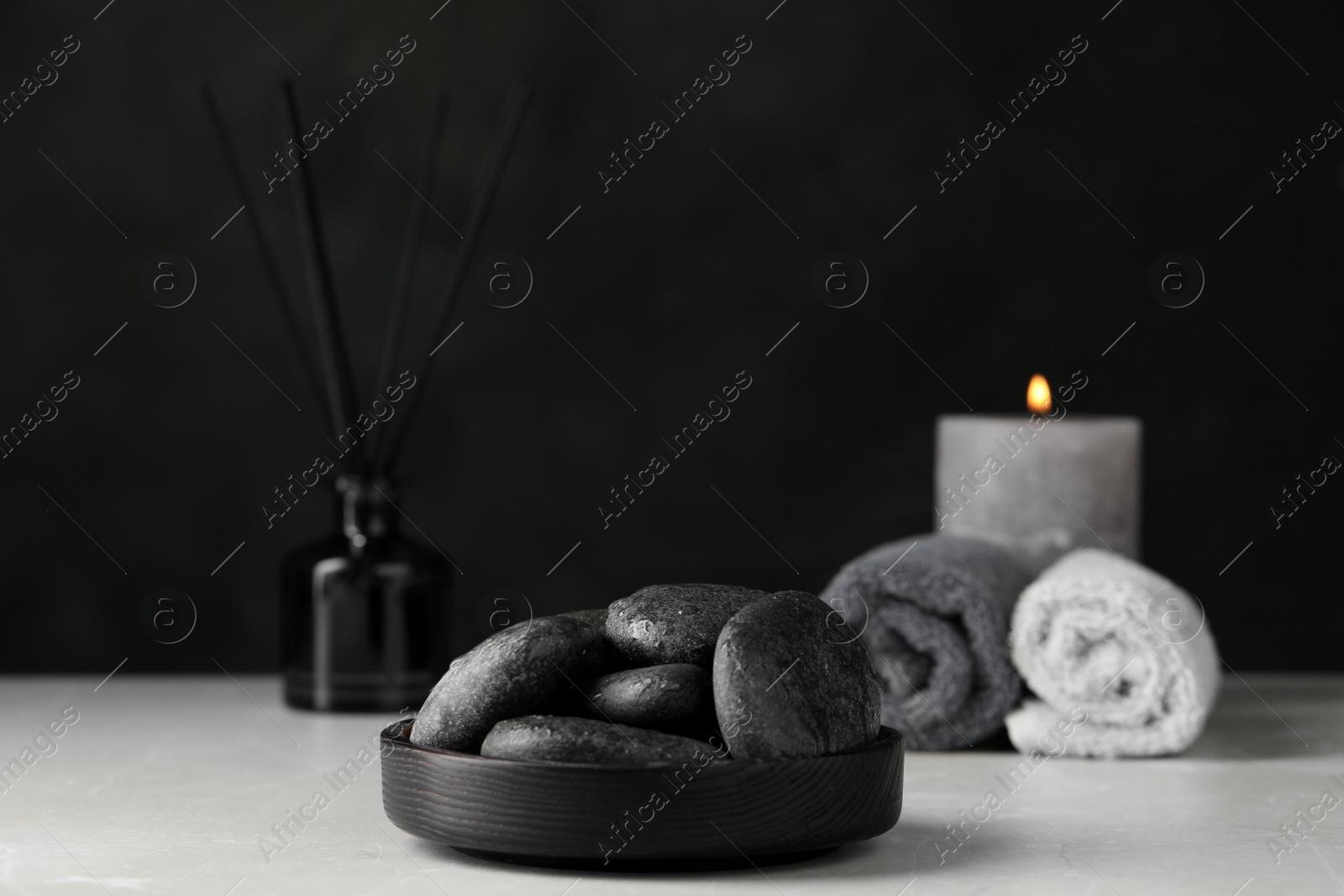 Photo of Spa stones with water drops on light grey marble table against black background