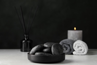 Photo of Spa stones with water drops on light grey marble table against black background