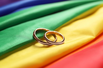 Wedding rings on rainbow LGBT flag, closeup