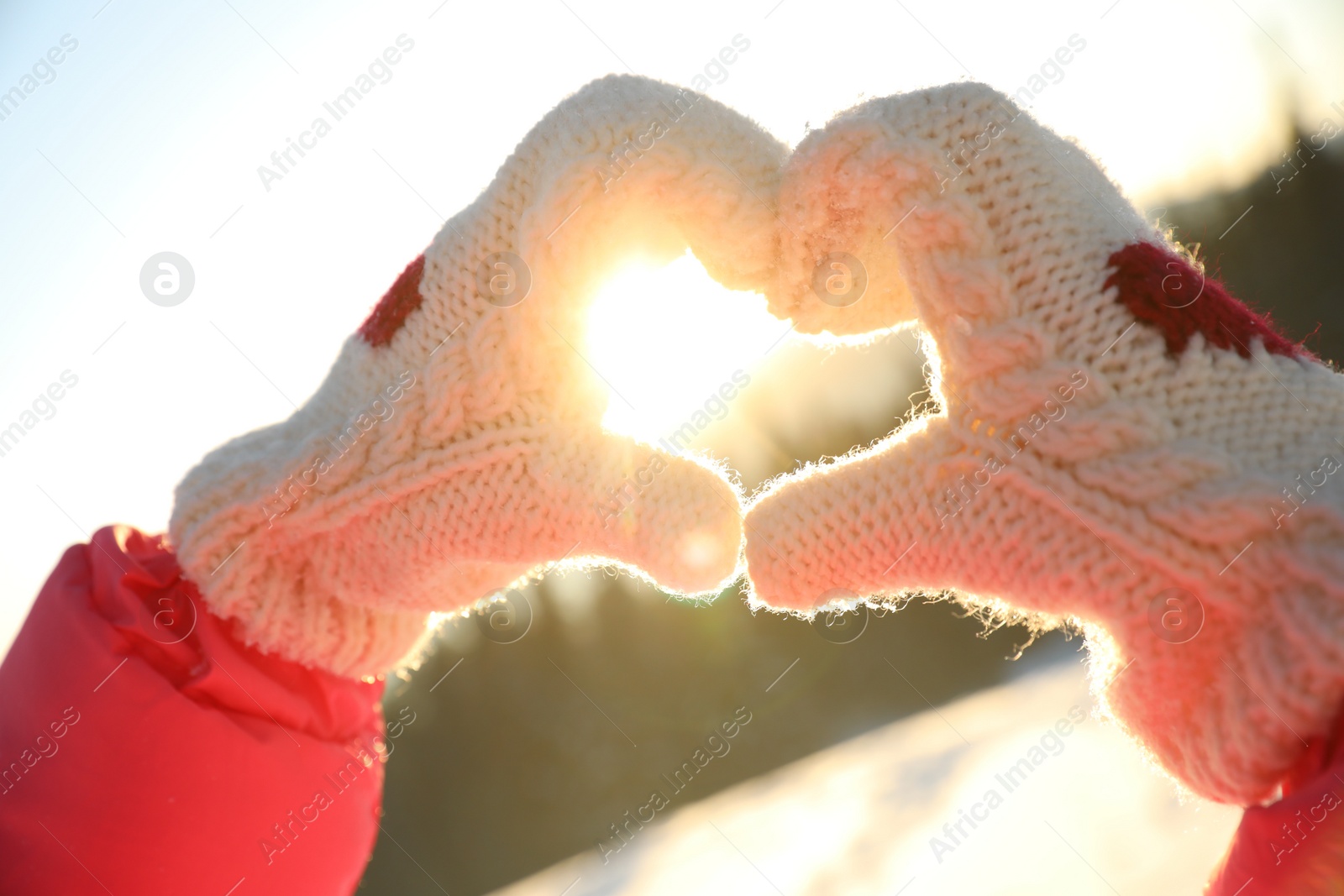 Photo of Woman making heart with hands outdoors at sunset, closeup. Winter vacation