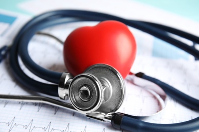 Photo of Stethoscope, red heart and cardiogram on table. Cardiology concept