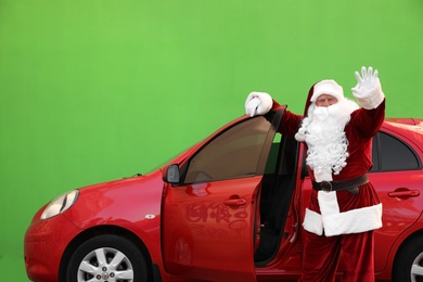 Authentic Santa Claus near car against green background