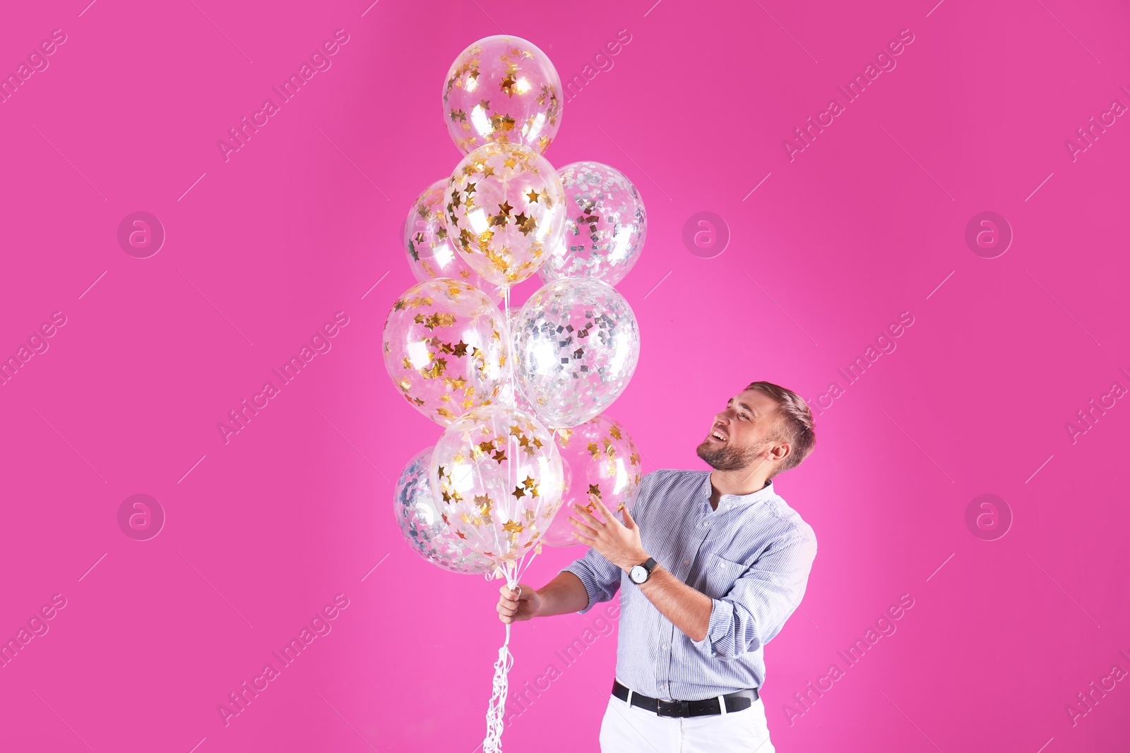 Photo of Young man with air balloons on color background