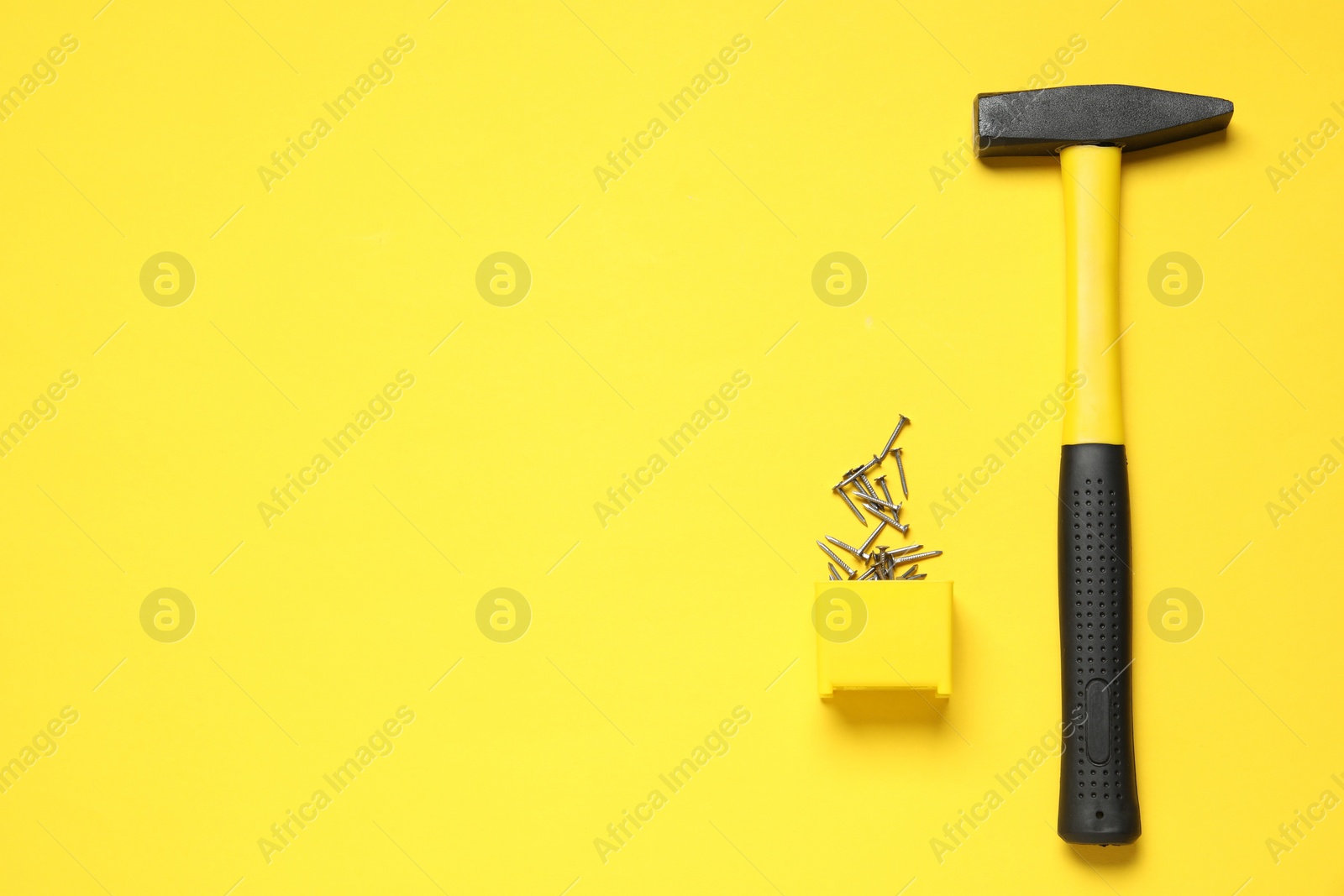 Photo of Hammer and metal nails on yellow background, top view. Space for text